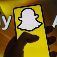 A phone displays the Snapchat logo in front of a screen that reads "My AI". 