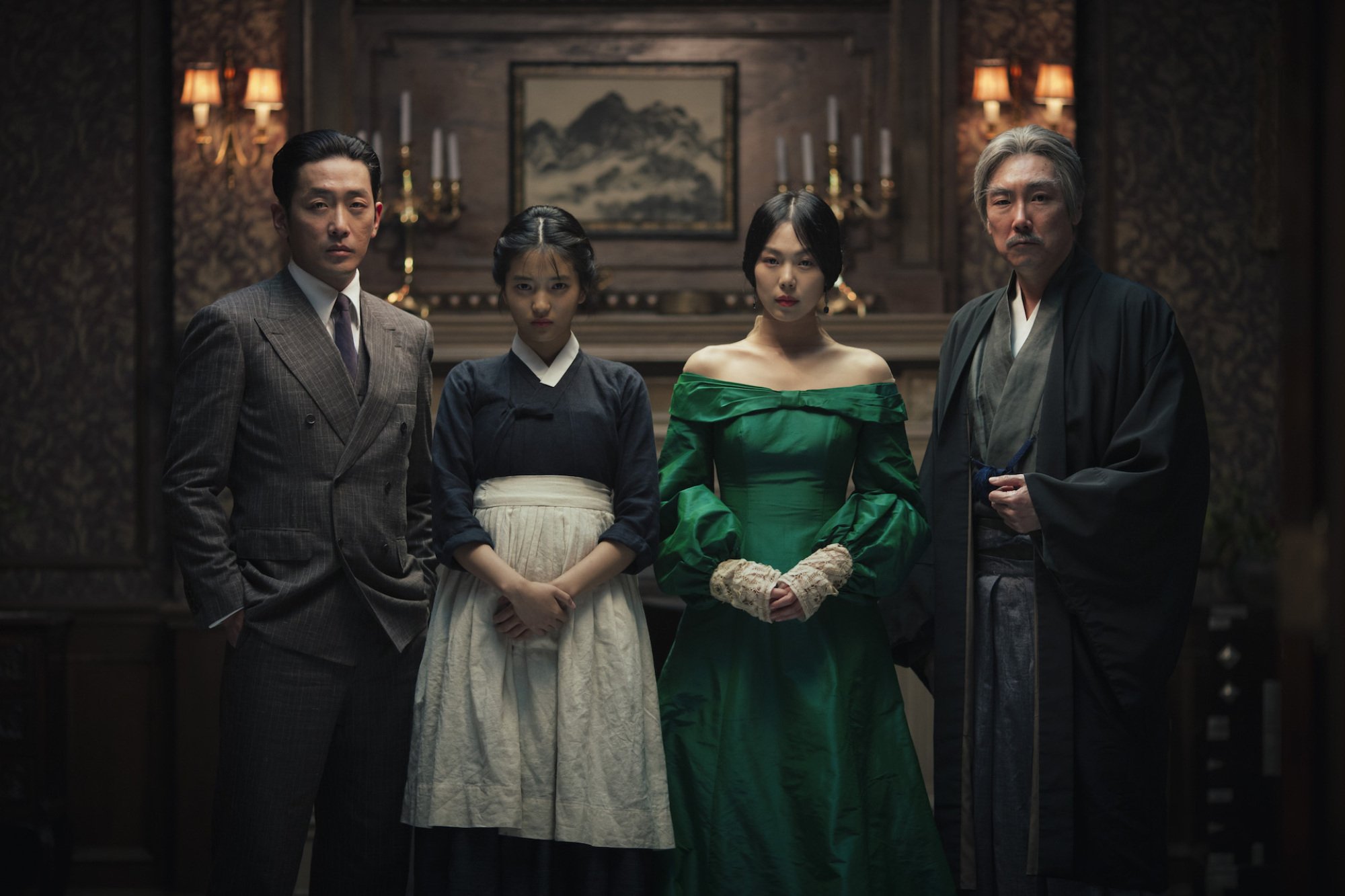 Two Asian men, one in a suit and the other in traditional clothes, stand around two Asian women, one of whom is in a maid's outfit, the other in a green dress.