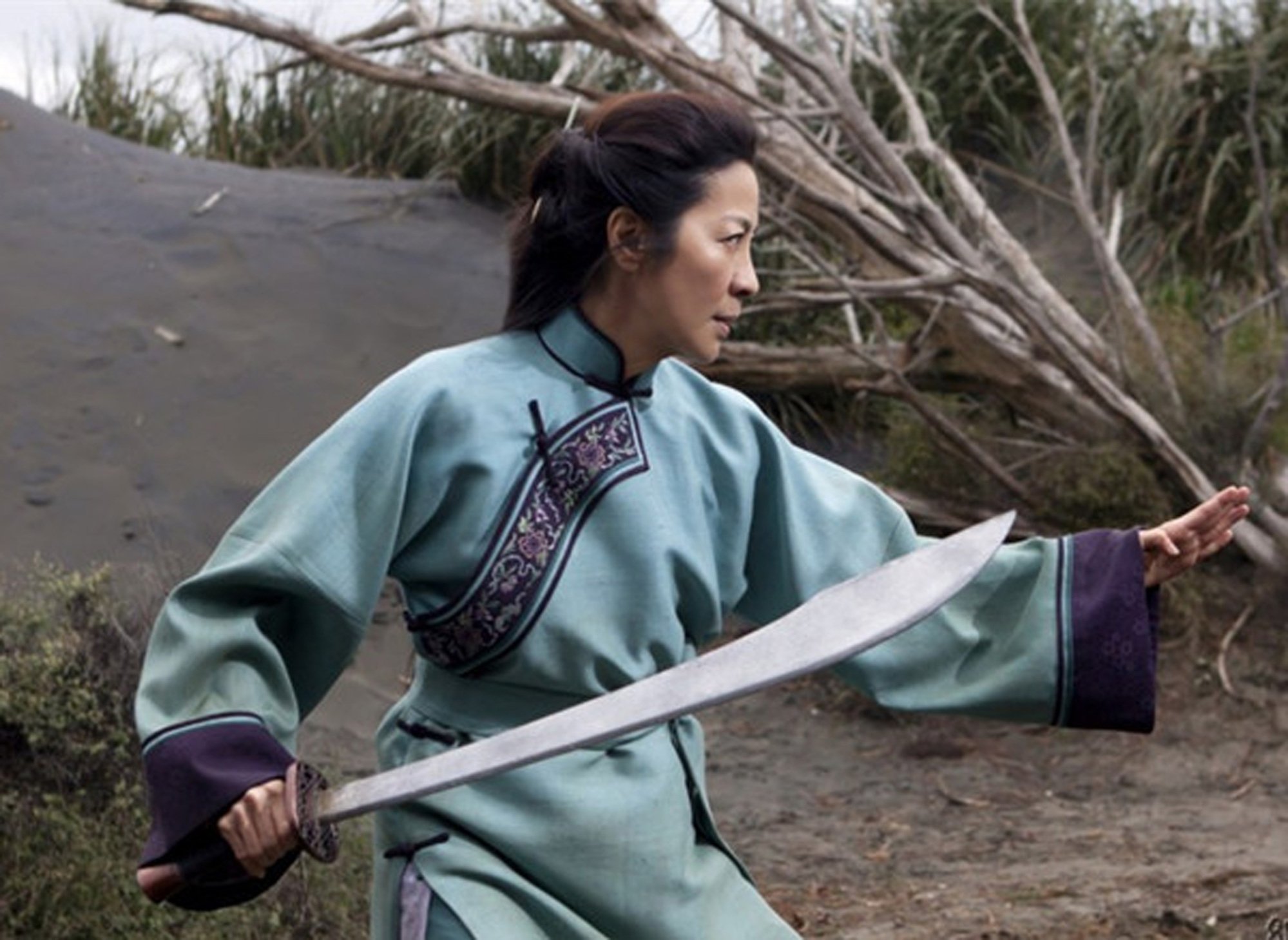 An Asian woman holds a sword and her hand out