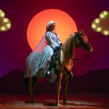 Malala Yousafzai sits on a fake horse in the show "We Are Lady Parts"