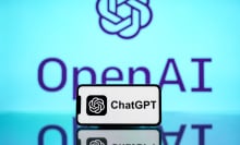 The ChatGPT logo is seen displayed on a mobile phone screen with OpenAI logo in the background.