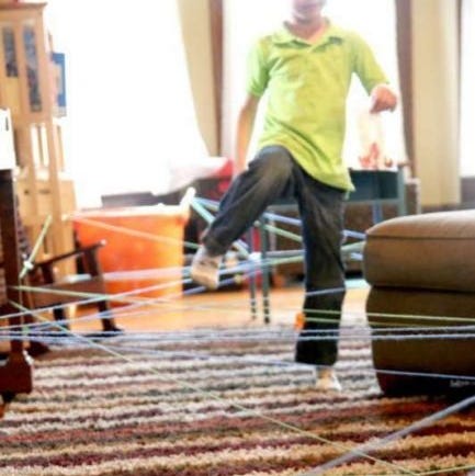 kids are stepping around a yarn spider web to find bug stickers  the project is a good housekeeping pick for best activities for kids