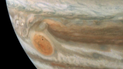 A tiny black dot hovers over Jupiter's Great Red Spot.