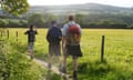 Three middle-aged men walking across the South Downs way.