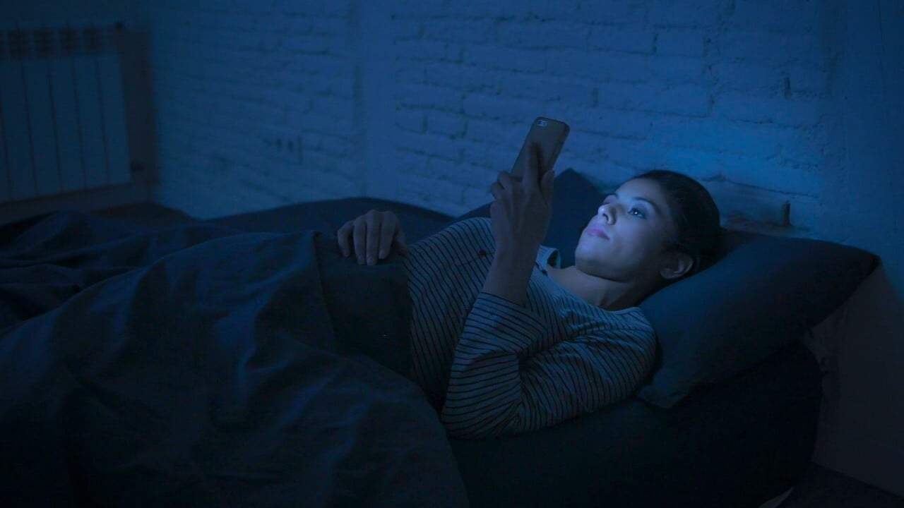 woman in bed with a bright phone screen