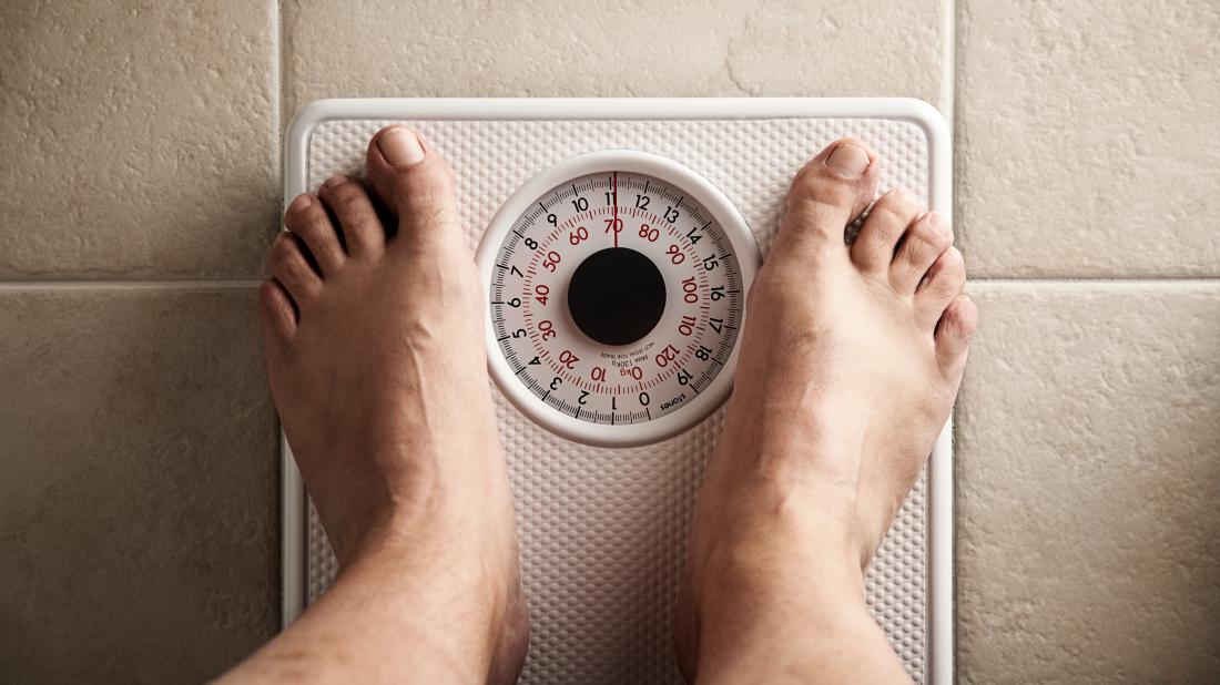 a mans feet on some scales as he is seeing if the keto diet is any good and made him lose weight