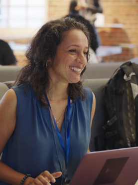 A woman working behind the laptop, smiling.