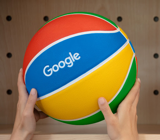 A person holds a Google-colored basketball.