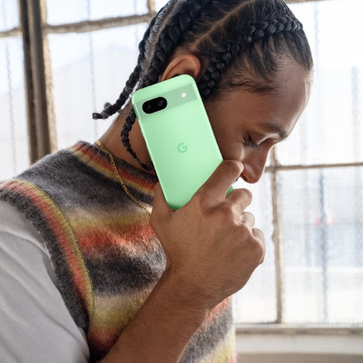 A person takes a call on their Pixel 8a in Aloe color.
