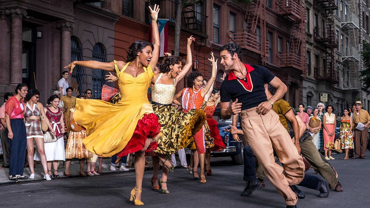 Actors Ariana DeBose and David Alvarez dancing in a street along with several others from the 20th Century Studios movie "West Side Story".