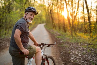 A senior man on his mountain bike outdoors in the forest.