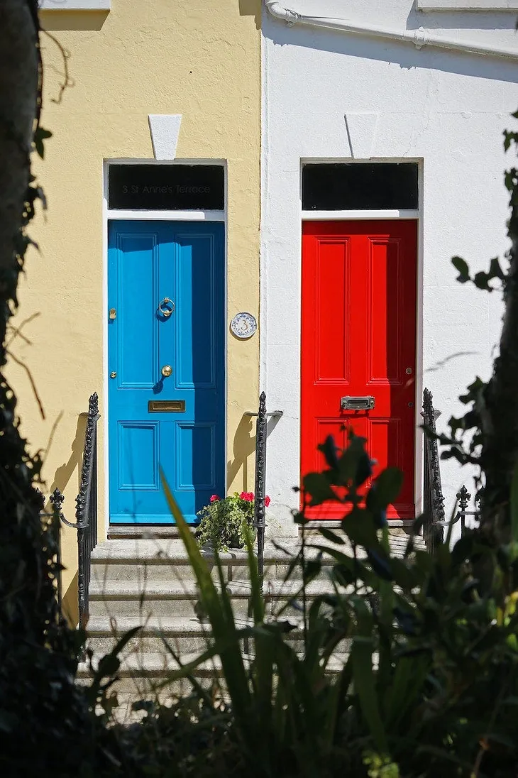 two doors side by side, one blue on the left, one red on the right.