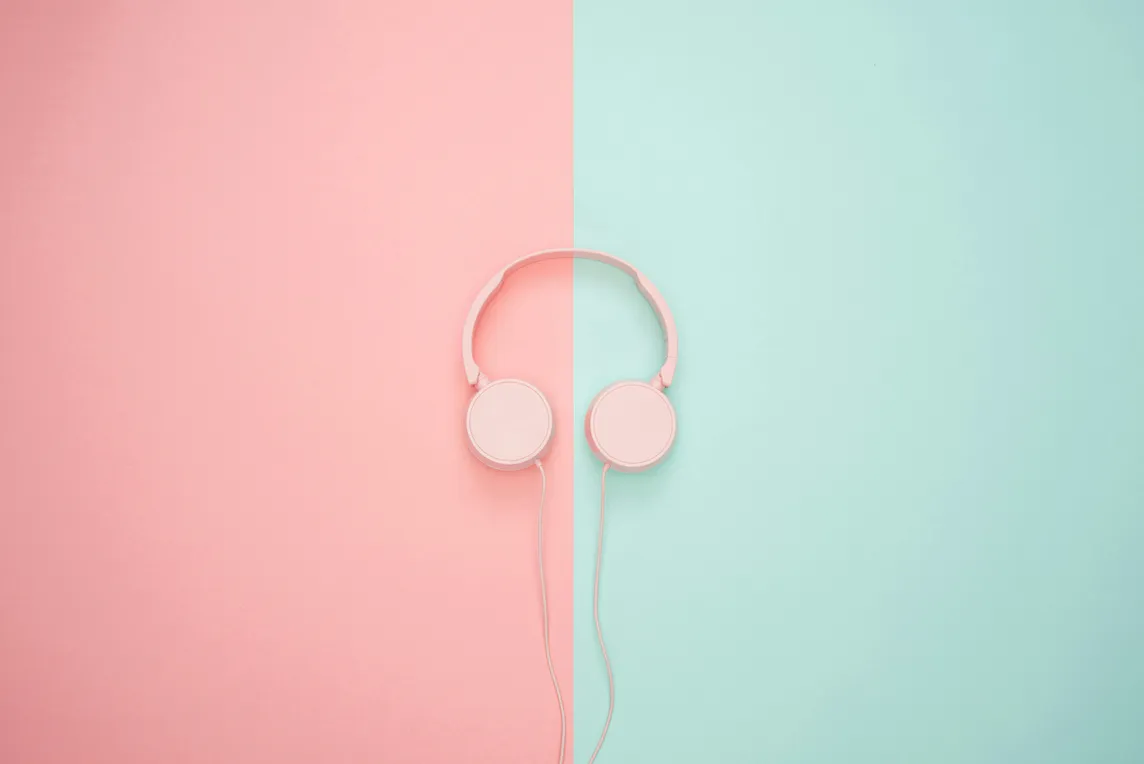 A pair of headphones against a pink and blue background split in half