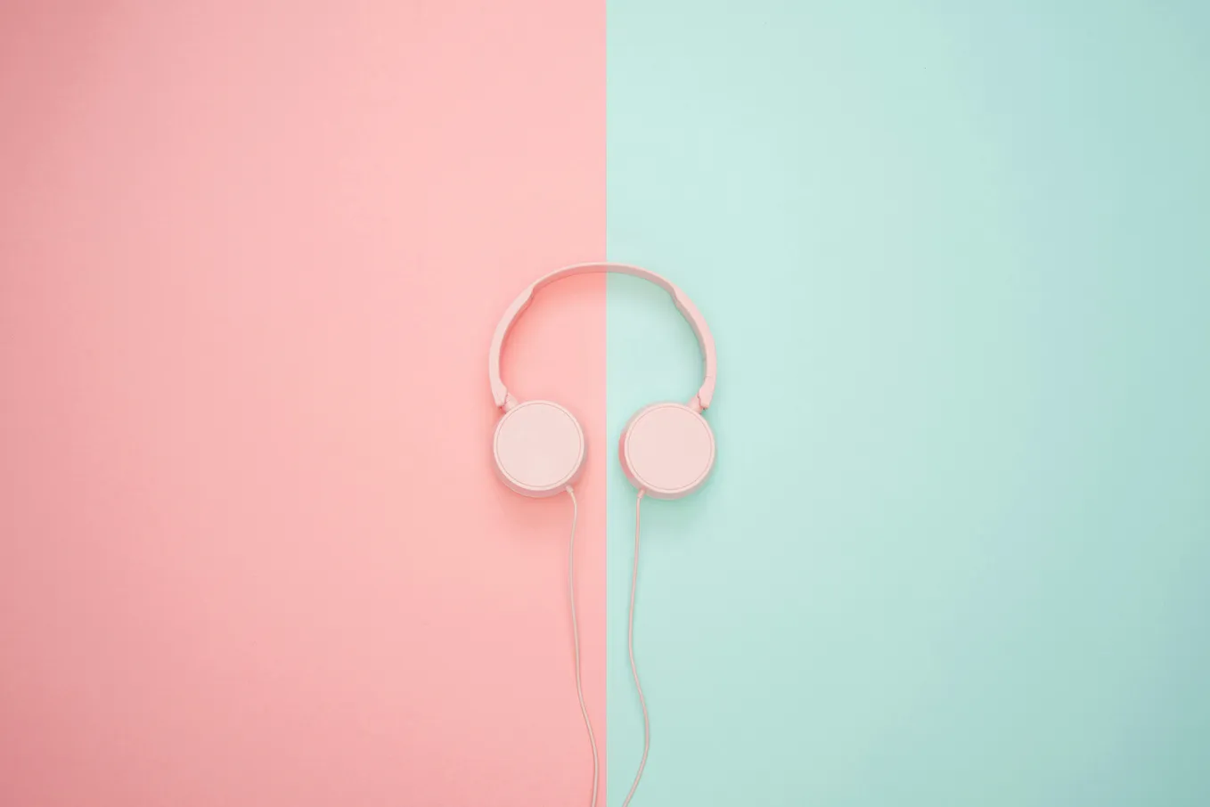 A pair of headphones against a pink and blue background split in half