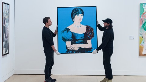 Two people move an Andy Warhol painting of Princess Diana.