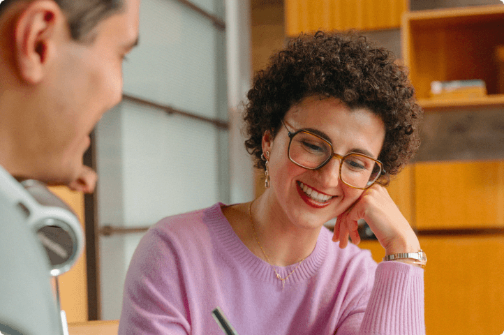 Woman smiling while collaborating with coworker in warm toned office