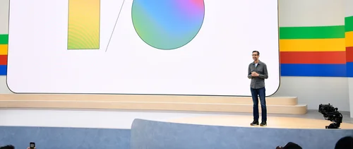 Image of Sundar on stage against backdrop showing the letters I / O with gradient colors filled in.