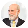 Vint Cerf, wearing a suit with a yellow polka-dot tie, looks to the left while smiling