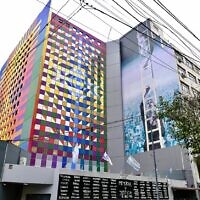 The colorful new facade of Buenos Aires' AMIA Jewish center abuts a mural painted to memorialize the 1994 bombing that killed 85 people there. (Juan Melamed/JTA)